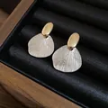 Gros plan détaillé montrant la texture métallique des boucles d'oreilles feuilles bicolores - Style avec Tige en Argent (HE33577) / Or et Argent