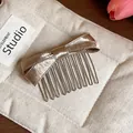 Detailed macro view of an elegant champagne satin bow hair comb with metallic teeth. - Hair Stick / Champagne Gold