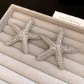 Close-up detail of silver starfish stud earrings with unique wrinkled texture finish - Silver