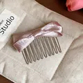 Detailed macro view of a pink satin bow hair comb on a soft beige fabric background - Hair Stick / Pink