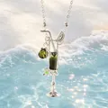Nahaufnahme einer Cocktailglas-Halskette mit grünen Steinen vor einem sonnigen Strand - Dunkelgrün