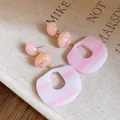 Close-up of marbled pink acrylic earrings with silver needle studs on canvas background - Pink