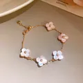Close-up of elegant pink mother of pearl flower charms on a delicate gold chain bracelet. - Five-Flower Mother of Pearl Bracelet / Pink Gold