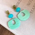 Detailed macro view of layered acrylic oval earrings in olive, blue, and mint green finish - Green