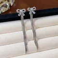 Detailed close-up of zircon bow earrings with long silver tassels on jewelry display - Bowknot Style (1#) / Silver