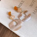 Close-up of elegant acrylic oval pendant earrings with a unique marble texture on fabric - White-Coffee