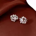 Detailed macro shot of sparkling floral cluster cubic zirconia ear clips on brown satin fabric - Clip-On Earrings / Silver