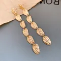 Primer plano de pendientes largos dorados con textura martilleada y diseño multiajustable - Pendientes de botón / Dorado