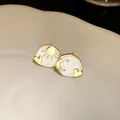 Close-up of asymmetrical sun and moon stud earrings with white enamel finish - Silver Earring Post-White
