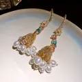Close-up detail of luxury parrot tassel earrings with sparkling crystals and white pearls - Silver Earring Post Style / Gold