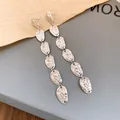 Primer plano detallado de pendientes largos de metal plateado con diseño de arrugas - Pendientes de botón / Plateado