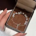 Detailopname van een verstelbare armband met zirkonia strikjes en parels in een geschenkdoos. - Schuifarmband / Zilver-Roze