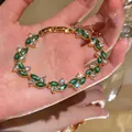 Vista dettagliata di un elegante bracciale placcato oro con zirconi verdi taglio marquise - Oro-Verde