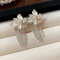 Detailed macro view of silver floral earrings with elegant pearl centers and tassels - Flower Tassel Style / Silver