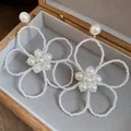 Elegant close-up view of French vintage pearl flower drop earrings in a wooden jewelry box. - Silver Earring Post Style / White
