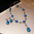 Close-up view of elegant blue teardrop crystal jewelry set with necklace and earrings - Blue