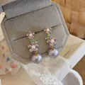 Close-up of elegant purple zircon flower earrings with large grey pearl drops - Gold