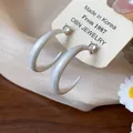 Detalle macro de pendientes de aro en C con circonita brillante y acabado de esmalte mate - Pequeño / Blanco