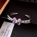 Detaillierte Nahaufnahme eines eleganten silbernen Armreifs mit rosa Zirkonia-Schmetterling. - Schmetterling Offener Armreif / Silber-Rosa