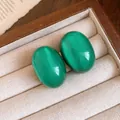 Close-up of green resin oval stud earrings with a cat-eye effect in a jewelry box - Emerald Green (Silver Post)