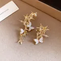 Close-up detail of gold asymmetric branch ear cuffs with white shell butterfly elements - Clip-On (Asymmetric Butterfly) / Gold