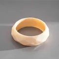 Dettaglio di un bracciale rigido in acrilico sfaccettato crema con finitura geometrica - Bianco