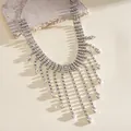Elegant detail of vintage rhinestone teardrop tassel necklace displayed on a stone prop. - Silver