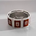 Primo piano dei dettagli in smalto marrone e del motivo a spirale argento di questo bracciale - Argento-Caffè