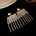 Gros plan de boucles d'oreilles à pampilles en strass avec clous en perles rondes - Or
