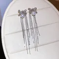 Detailed view of elegant silver bow tassel earrings with sparkling zircons and pearls - Bow Tassel / Silver