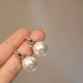 Vista macro che mostra la trama e la forma rotonda degli orecchini con perle bianche. - Perla Geometrica / Argento