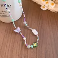 Close-up detail of a handmade beaded necklace with butterfly and flower pendants. - Silver Multicolor