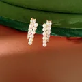 Close-up of elegant gold-tone earrings with vertical rows of pearls and clear crystals - Silver Post (HE33852) / Gold-White