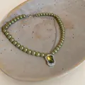 Detail showing green pearl necklace with a brilliant emerald green zircon pendant on a tray - Necklace-Green