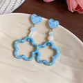 Primer plano de pendientes de corazón azul con detalle de concha y aros festoneados - Perno de plata-Azul