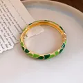 Detail of gold-plated buckle bracelet featuring green enamel dripping oil patterns - Gold/Green