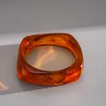 Macro view of translucent amber resin bangle with elegant marble swirl pattern - Geometric Square Bangle / Brown