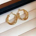 Macro detail of 18K gold plated twisted hoop earrings in a beige display box - Gold