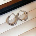 Close-up detail of silver-tone double-layered twisted hoop earrings in a jewelry box - Silver