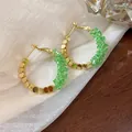 Close-up detail of 14K gold plated hoop earrings featuring vibrant green crushed crystals. - Gold-Green