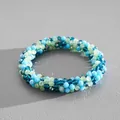 Detailed macro view of multi-color crystal beaded bracelet on gray textured surface. - Bracelet / Blue Green