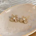 Close-up of elegant flower stud earrings with pavé zircons and faux pearls. - Gold