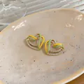 Detail view of heart-shaped earrings with green and yellow enamel and zircon - Gold-Green
