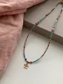 Close-up detail of vintage bohemian beaded necklace with a delicate golden flower pendant - Flower Dangle Style / Necklace Gold Colorful