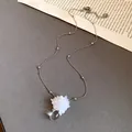 Zoom sur une fleur en paillettes blanches et un pendentif goutte d'eau sur chaîne argentée - Blanc Argenté
