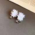 Gros plan de boucles d'oreilles fleurs en paillettes blanches avec gouttes d'eau - Blanc