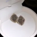 Nahaufnahme eleganter goldfarbener Rauten-Ohrstecker mit Pavé-Kristallen - Silberner Ohrstecker - Gold - Grau