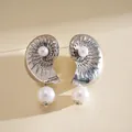 Macro detail of elegant silver seashell earrings featuring lustrous pearls for a vacation look - Silver Needle / Silver