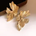 Primo piano di orecchini geometrici irregolari dorati con elegante finitura strutturata e design - Oro