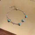 Close-up detail of a silver-toned chain bracelet with turquoise beads and stones - Silver-Blue